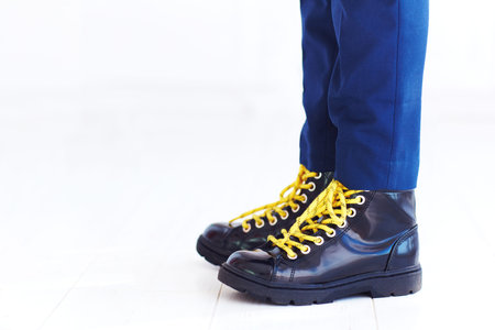 stylish look of patent leather ankle boots with yellow shoelaces and socks at young boy