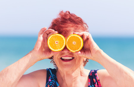 funny portrait of mature woman, grandma having fun with orange eyes on summer vacationの写真素材