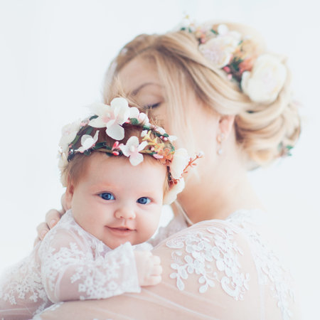 tender portrait of young mother holding infant baby girl, daughter. family look outfitの写真素材
