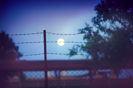 barbed wire fence at the countryside ranch under the moon light, summer nightの写真素材