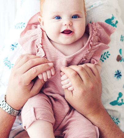 top view of father playing with cute infant baby daughter in bed, at homeの写真素材