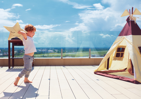 happy young boy, kid playing near the textile wigwam tent on the summer patioの写真素材