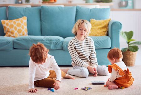 cute kids, siblings playing on the floor at homeの写真素材