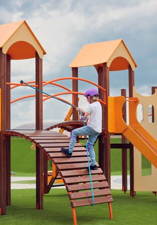 happy boy climbing into colorful activity tower on the playground, children development and entertainment, playground equipmentの写真素材