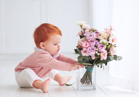cute, one-year-old baby girl with delicate flower bouquetの写真素材
