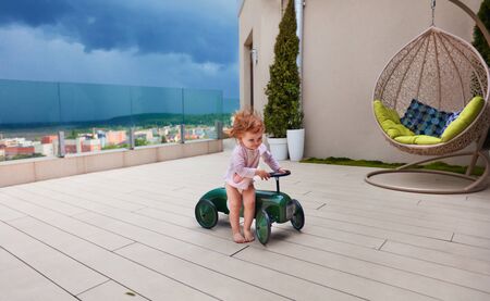 happy baby girl playing on the patio before the stormの写真素材