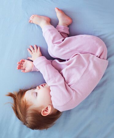 cute infant baby girl sleeps peacefully on the bedの写真素材