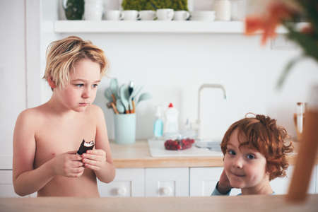 kids eating milk chocolate bars in the morning on the kitchenの写真素材