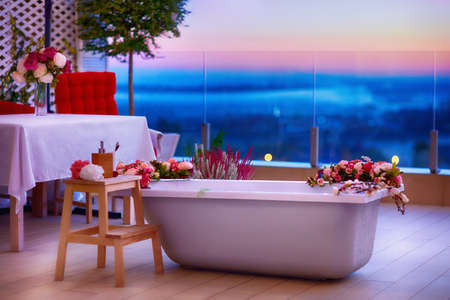 taking bath in bathtub with flowers at rooftop patio at warm summer nightの写真素材