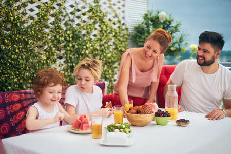 happy family having lunch on rooftop patio at homeの写真素材