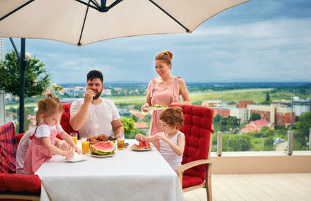 happy family having lunch on rooftop patio at homeの写真素材