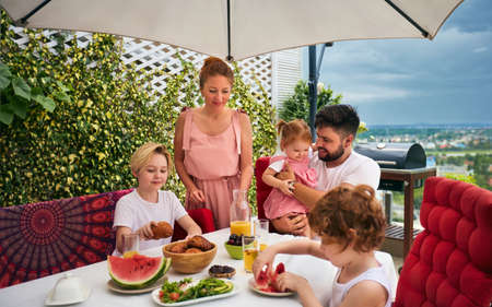 happy family having lunch on rooftop patio at homeの写真素材