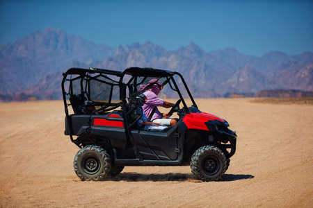 family is driving a buggy car through the desert. extreme tourism adventuresの写真素材