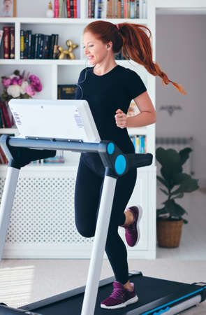 happy woman exercising on a treadmill at home, healthy lifestyleの写真素材