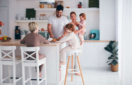 happy family with three kids having breakfast in the kitchen in the morningの写真素材