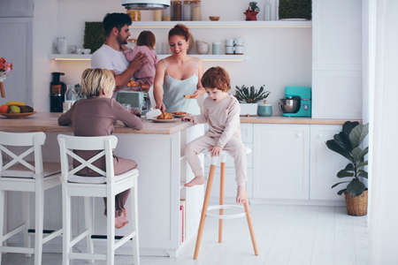 happy family with three kids having breakfast at the kitchen in the morningの写真素材