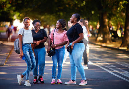 beautiful african american women, laughing friends having fun while walking on the streetの写真素材
