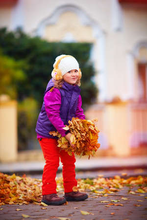 beautiful smiling girl having fun, playing with colorful leaves in autumn parkの写真素材