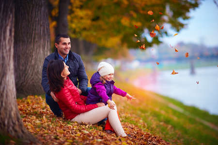 happy family playing among fallen leaves in autumn parkの写真素材