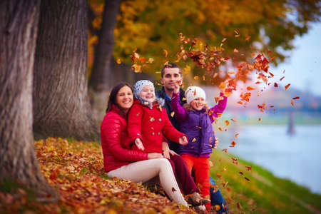happy family playing among fallen leaves in autumn parkの写真素材