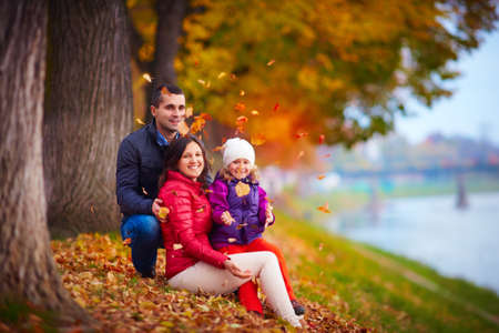 happy family playing among fallen leaves in autumn parkの写真素材