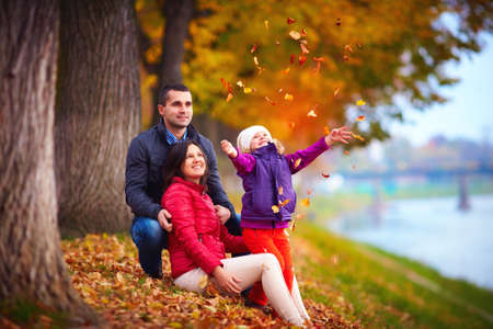 happy family playing among fallen leaves in autumn parkの写真素材