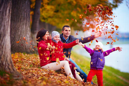 happy family playing among fallen leaves in autumn parkの写真素材