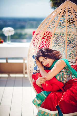 beautiful indian woman relaxing in hanging swing at the patioの写真素材