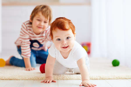 portrait of happy redhead infant baby boy crawling on the floor at homeの写真素材
