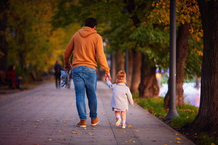 rear view of father with baby girl on the walk on the autumn streetの写真素材