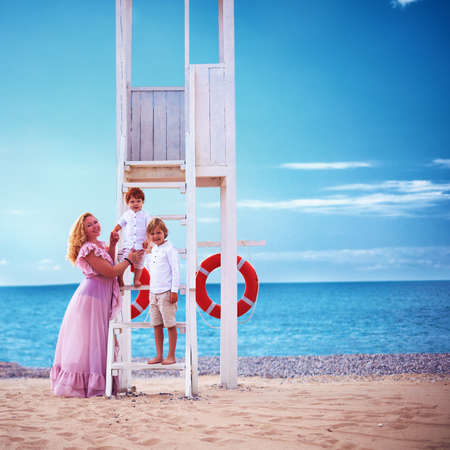 portrait of happy mother and kids posing at lifeguard tower during summer vacationの写真素材