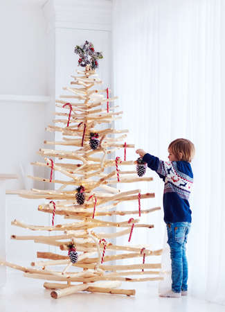 kid decorating the eco friendly, reusable christmas tree, with pine cones and christmas candy canesの写真素材