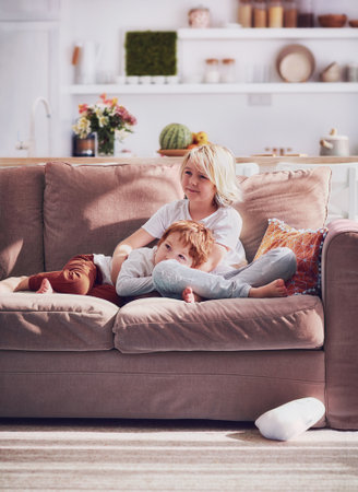 cheerful brothers relaxing on sofa at the living room. cozy home interiorの写真素材