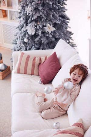 delighted baby boy playing with christmas tree ball ornaments at homeの写真素材