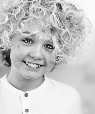 portrait of beautiful happy blonde boy with curly hair
