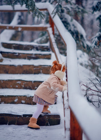 cute baby girl having fun in snowy winter parkの写真素材
