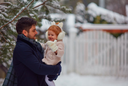 cheerful father with baby daughter having fun outdoors in winter snowの写真素材