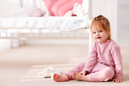 cute toddler baby girl sitting on the carpet in the nursery roomの写真素材