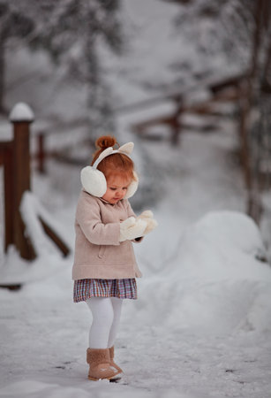 cute little baby girl having fun in winter park, playing with the snowの写真素材