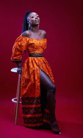 beautiful elegant african woman in traditional dress on red background, studio shotの写真素材