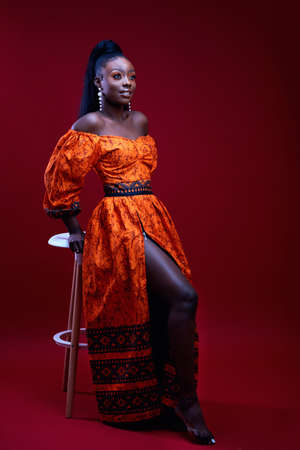 beautiful elegant african woman in traditional dress on red background, studio shotの写真素材