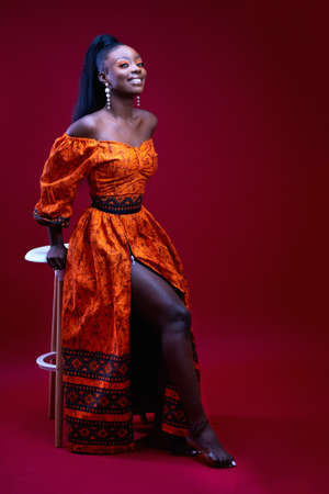 beautiful elegant african woman in traditional dress on red background, studio shotの写真素材