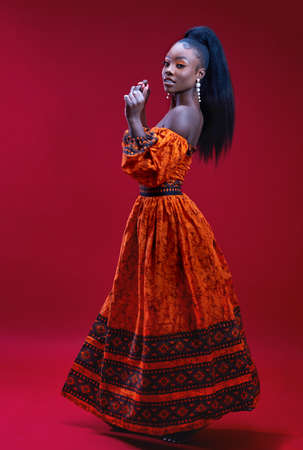 beautiful glamorous african woman in traditional dress dancing on red background, studio shotの写真素材