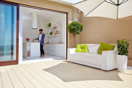 man cooking on cozy open space kitchen with rooftop patio and sliding doorsの写真素材