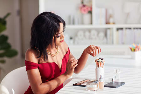 Beautiful African American Woman applying her makeup on with professional cosmetics products at homeの写真素材