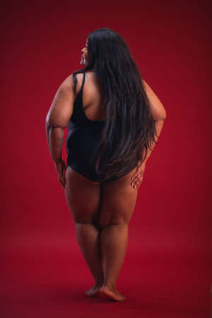 young plus size woman in swimsuit on the red backgroundの写真素材
