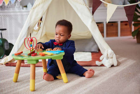 cute little baby boy playing with wooden developing toy on the carpet at homeの写真素材