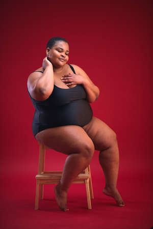 young plus size woman in swimsuit on the red background, diverse beautyの写真素材