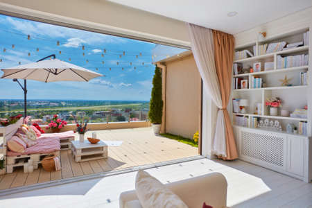cozy living room with open space rooftop patio, and wooden pallet furniture decorated with colorful pillows at warm summer dayの写真素材