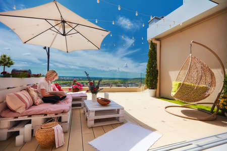 young boy relaxing on furnished rooftop patio at warm sunny dayの写真素材